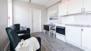 Een moderne keuken met witte kasten, een vaatwasser, en een eethoek met een tafel en stoelen.