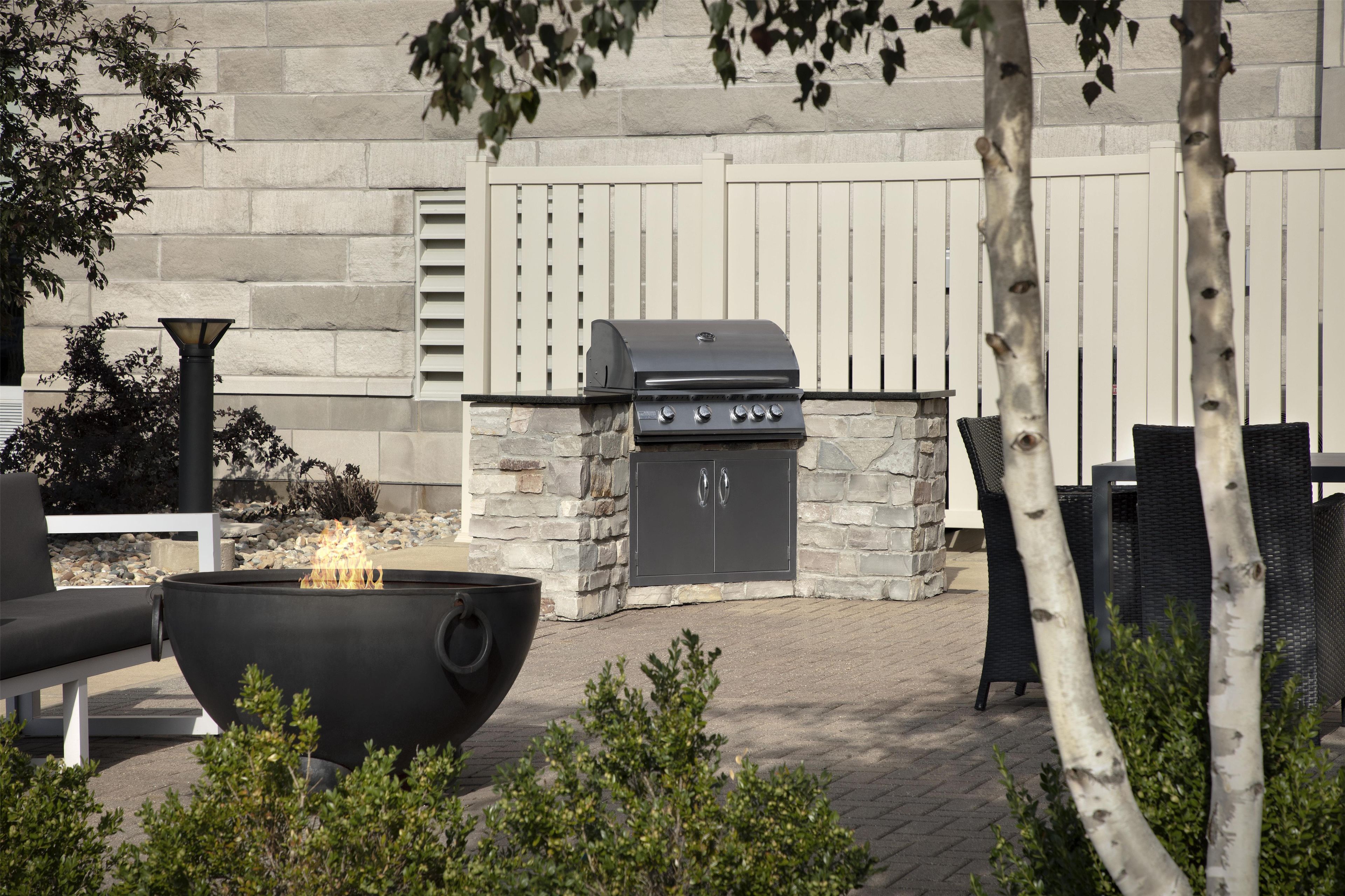 An outdoor patio with a stone barbecue grill, a fire pit, and outdoor seating.