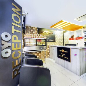 A hotel reception area with a reception desk, seating area, and a wall with a decorative pattern. - Hotel KL Centre Point (Kuala Lumpur)
