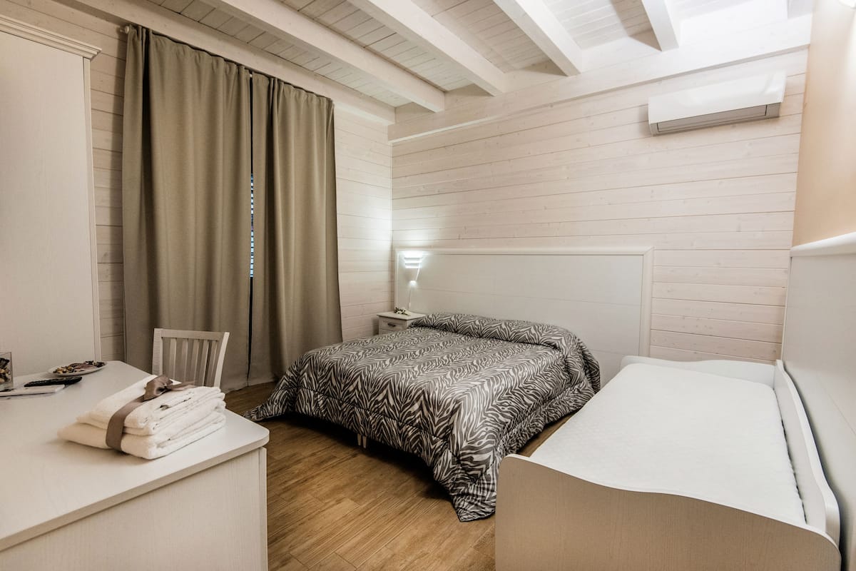 A bedroom with a bed, a desk, a chair, and a nightstand.