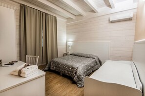 A bedroom with a bed, a desk, a chair, and a nightstand.