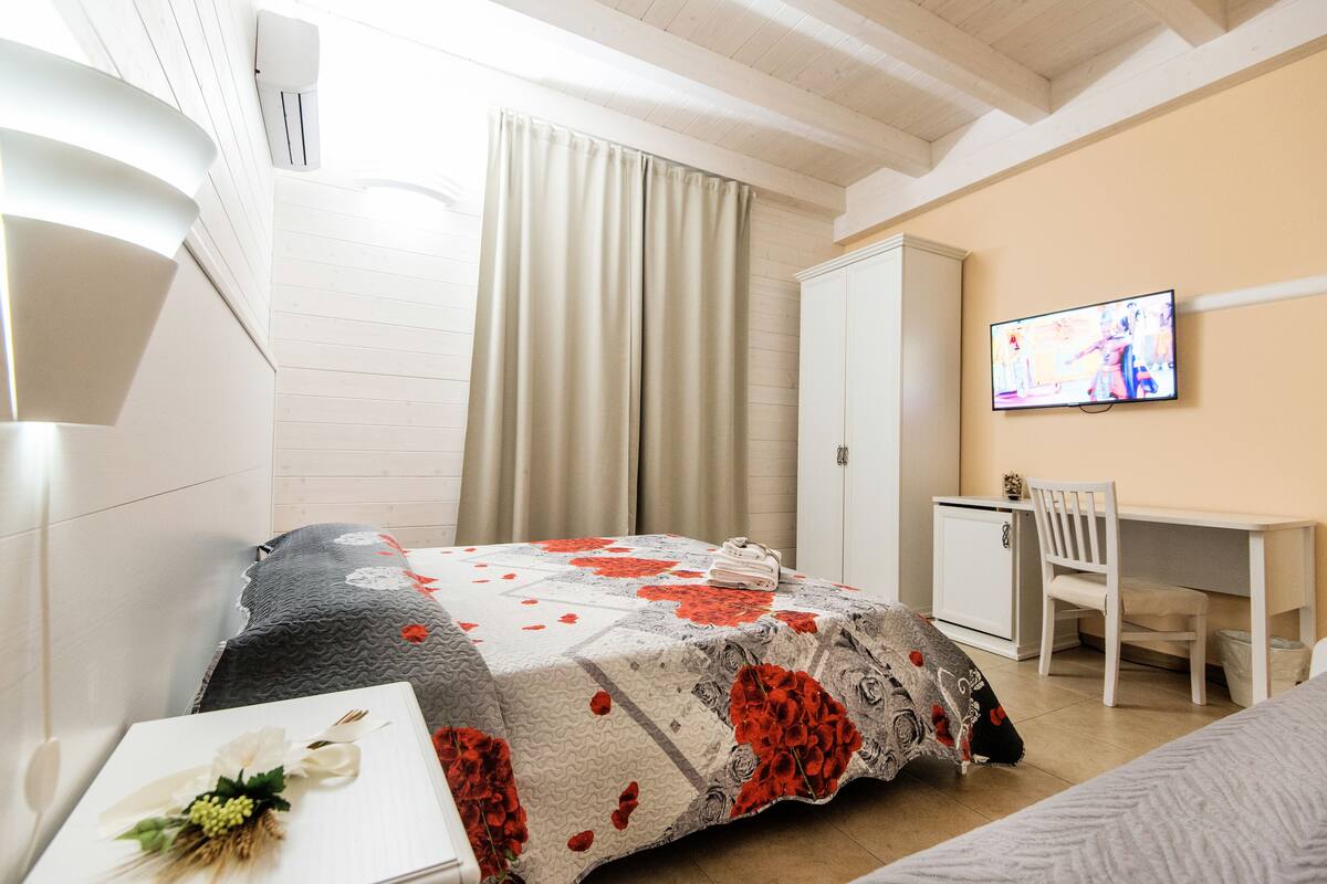 A hotel room with a bed, a desk, a television, and a wardrobe.