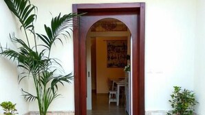 A hotel entrance with a wooden archway, tiled flooring, and potted plants. - Le Camelie (Ginosa)
