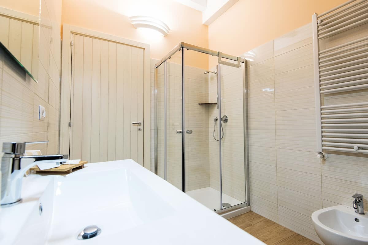 A modern bathroom with a large white sink, a glass-enclosed shower, and a white pedestal sink.