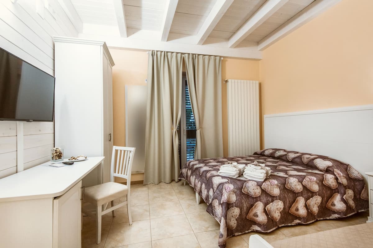 A bedroom with a bed, a desk, a chair, and a television.
