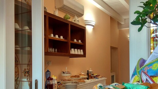 A kitchen area with a buffet setup, including a variety of food items and a coffee station. - Le Camelie (Ginosa)