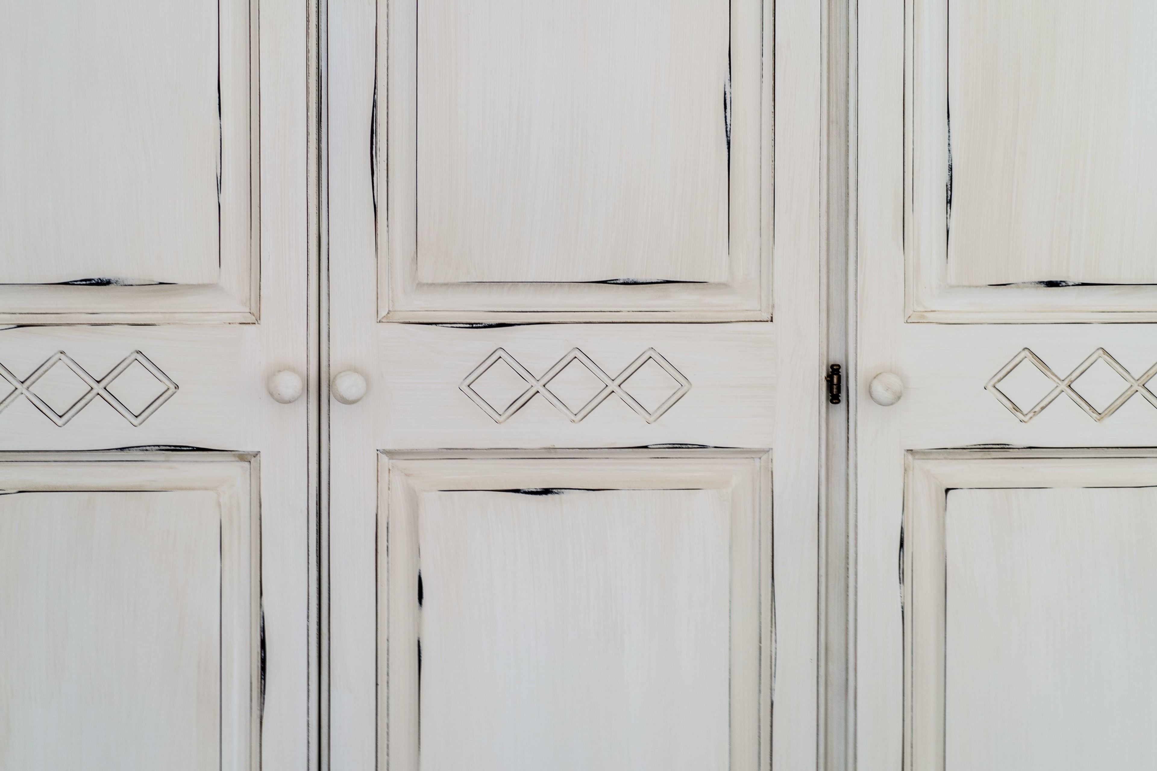 Una puerta blanca con un diseño geométrico y pomos redondos.