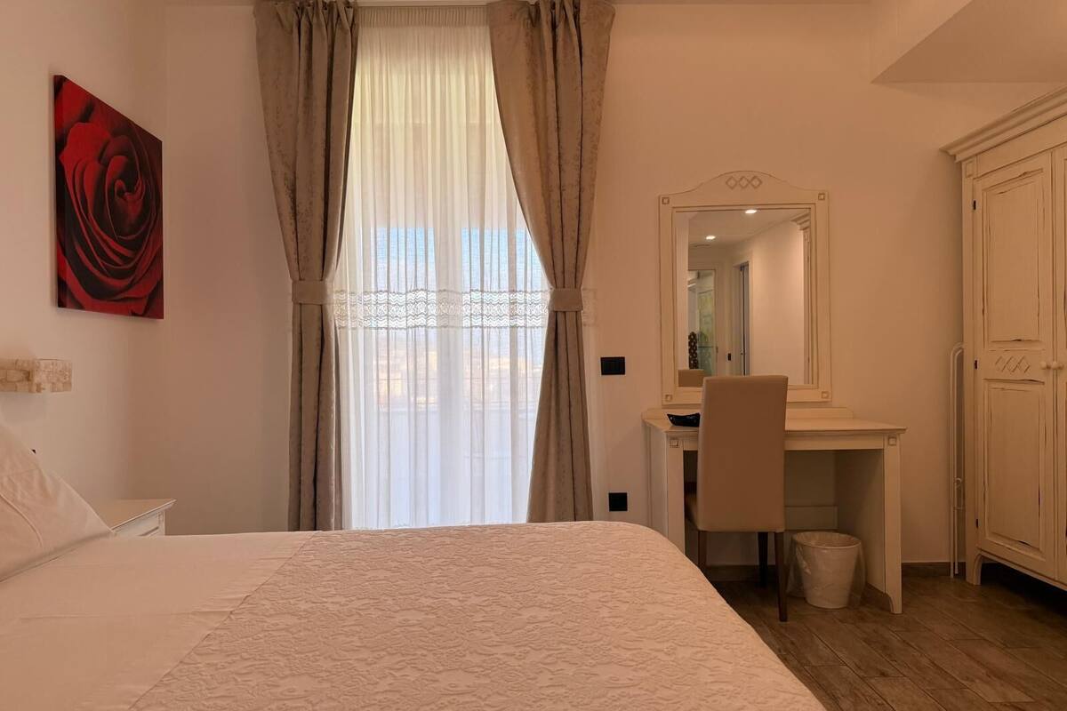 Ein Schlafzimmer mit einem Bett, einem Schreibtisch, einem Stuhl, einem Spiegel und einem Kleiderschrank.