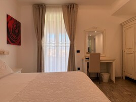 Un dormitorio con cama, escritorio, silla, espejo y armario.