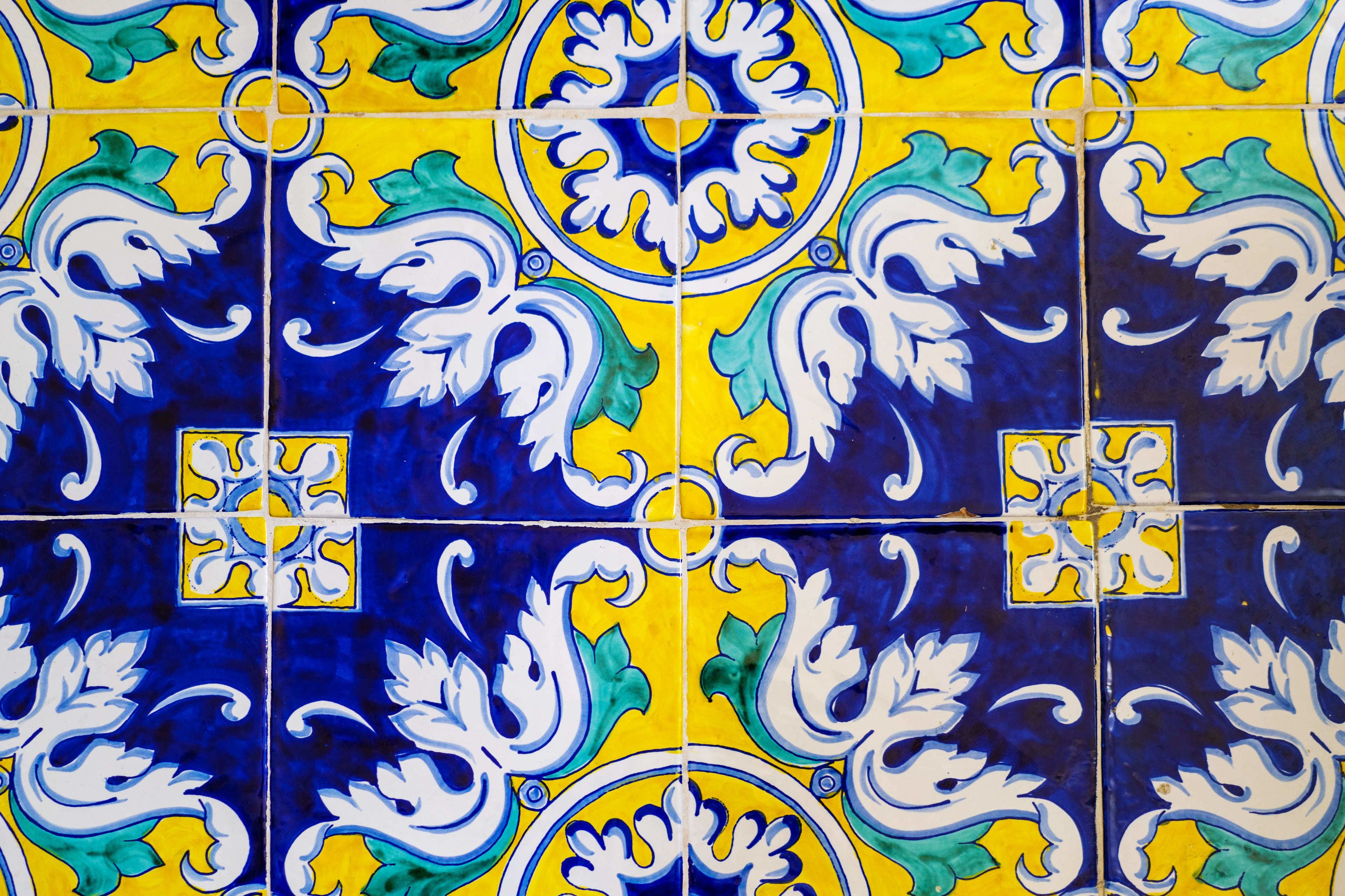 Een betegelde muur met een herhalend patroon in blauw, geel en wit.