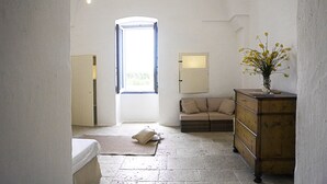 A room with a bed, a dresser, a sofa, a window, and a lamp. - Masseria Capece (Cisternino)