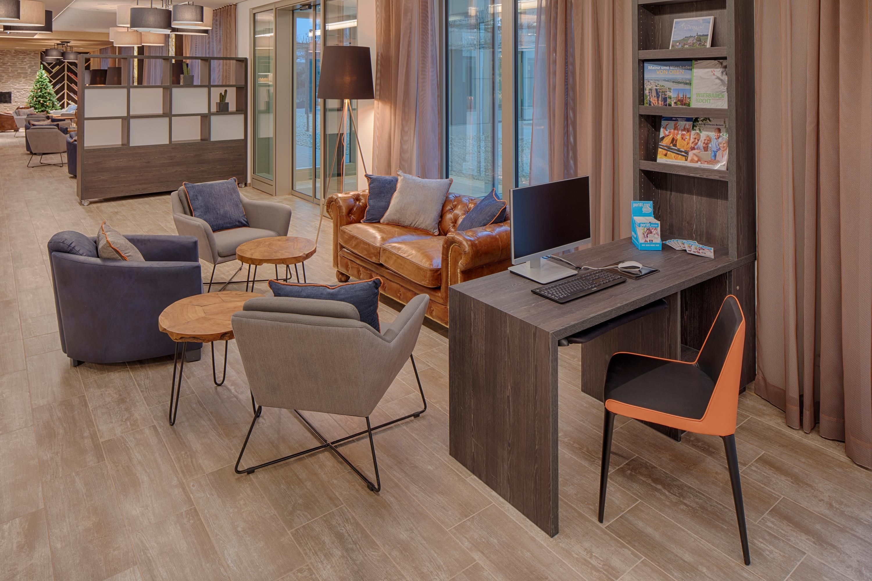 Eine moderne Hotelhalle mit Sitzgelegenheiten, einem Schreibtisch und einem Bücherregal.