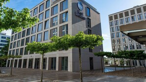 Un hotel moderno con un llamativo letrero de 'BW Best Western', varios pisos y un patio con árboles.