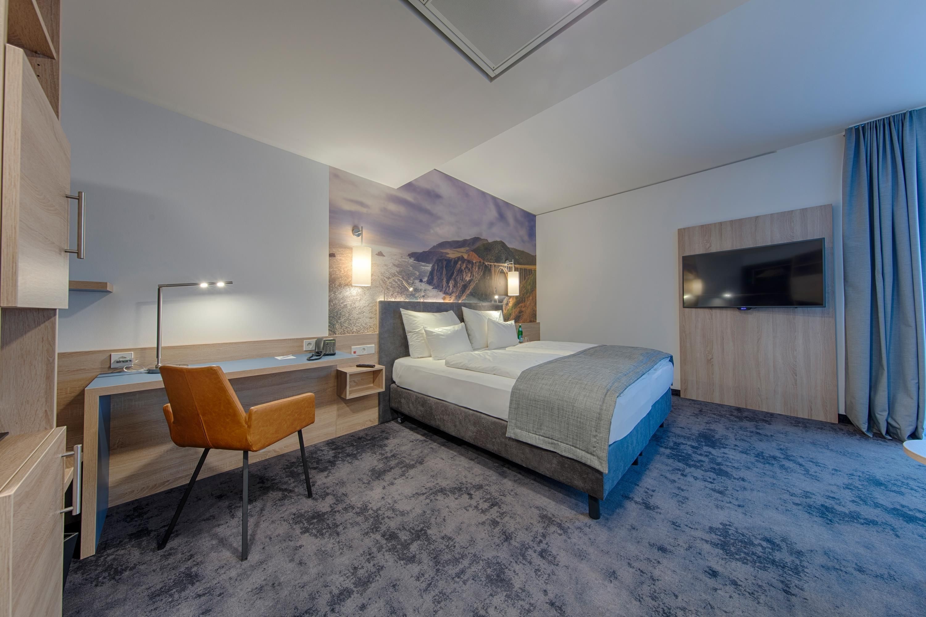 Une chambre d’hôtel équipée d’un lit, d’un bureau, d’une chaise et d’un téléviseur.
