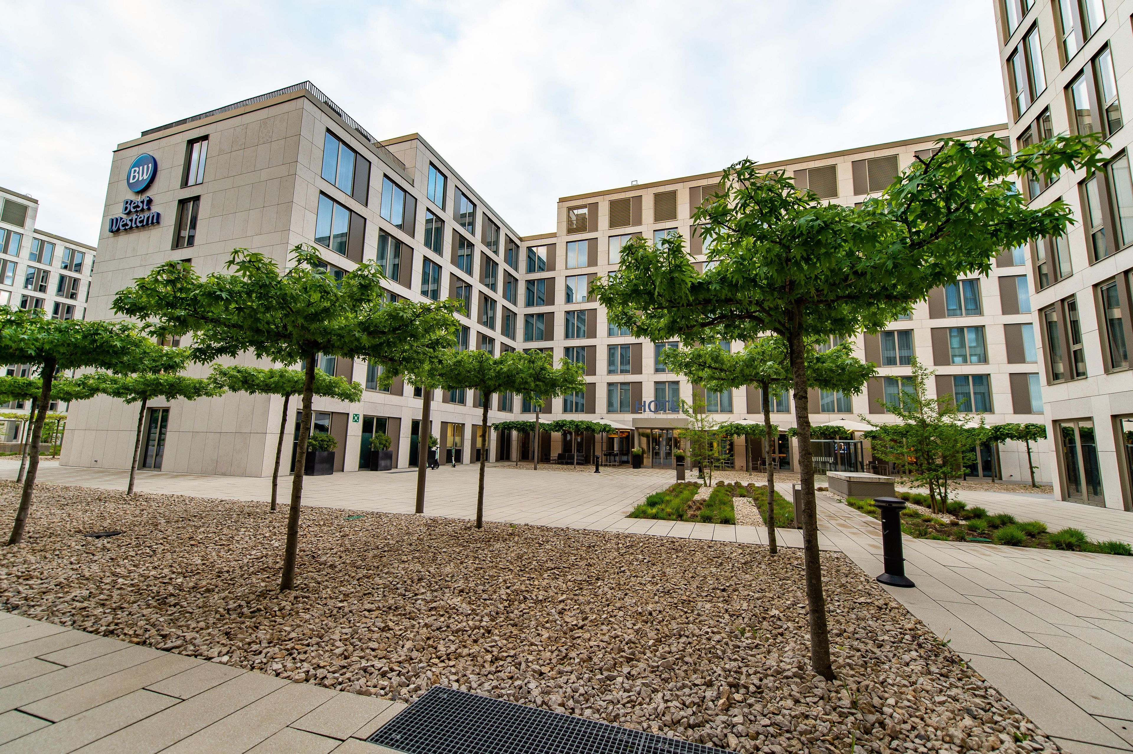 A hotel with a modern design, featuring a courtyard with trees and a gravel area.