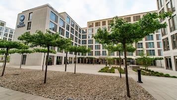 A hotel with a modern design, featuring a courtyard with trees and a gravel area.