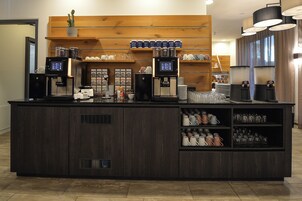 Una estación de café con dos máquinas de espresso, diferentes tazas de café y una variedad de tazas y vasos.