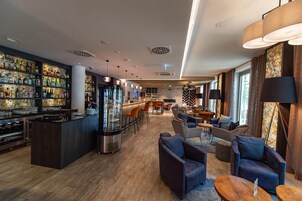 Una zona de bar con estantes llenos de botellas, una barra y asientos con mesas y sillas.