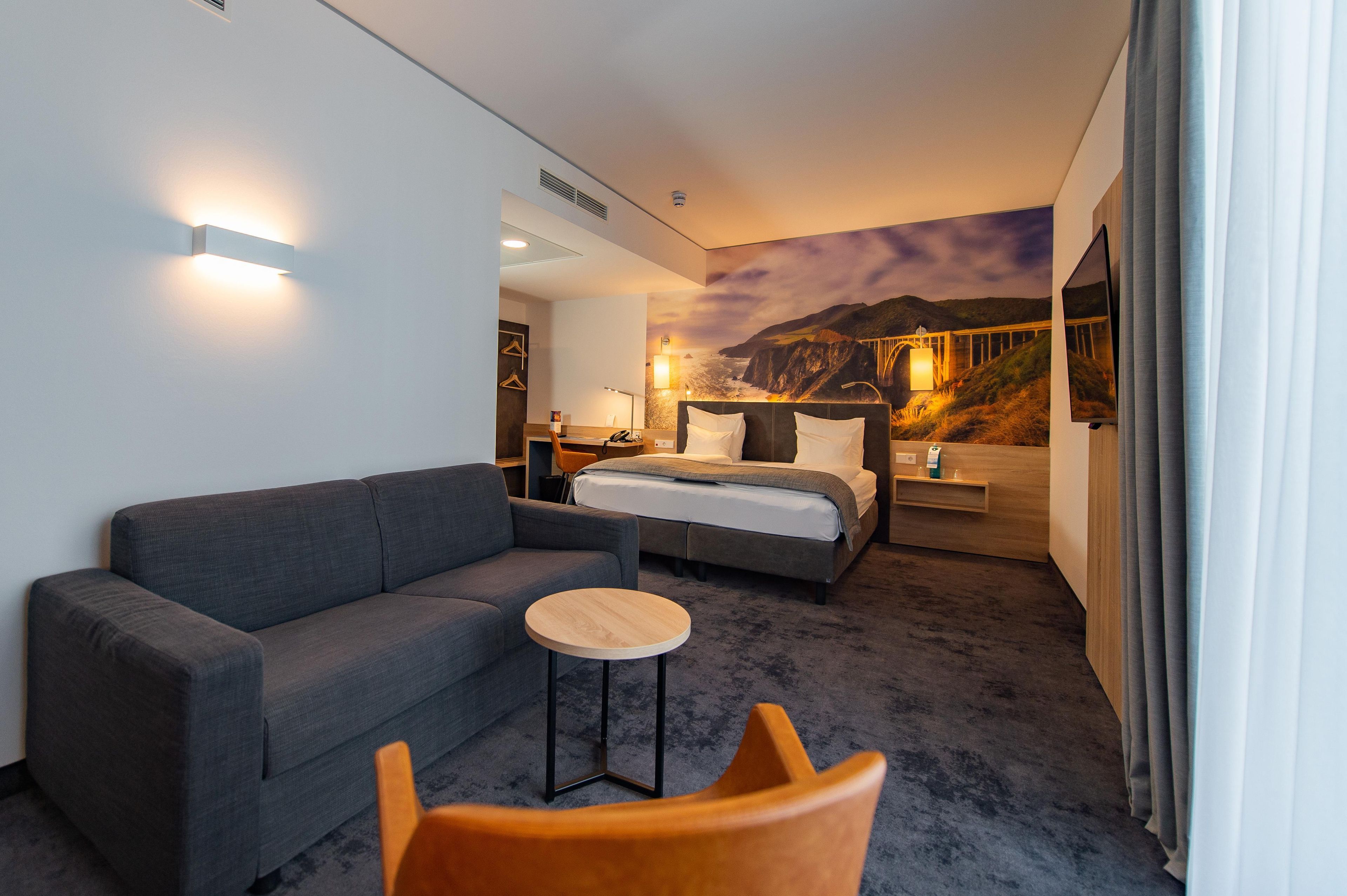 Ein Hotelzimmer mit einem Bett, einer Couch, einem kleinen Tisch und einem Sessel.