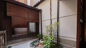 Un jardín japonés tradicional con un árbol pequeño, rocas y una estructura de madera.