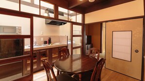 Una cocina tradicional al estilo japonés con una mesa de comedor de madera, sillas, un microondas y una estufa.