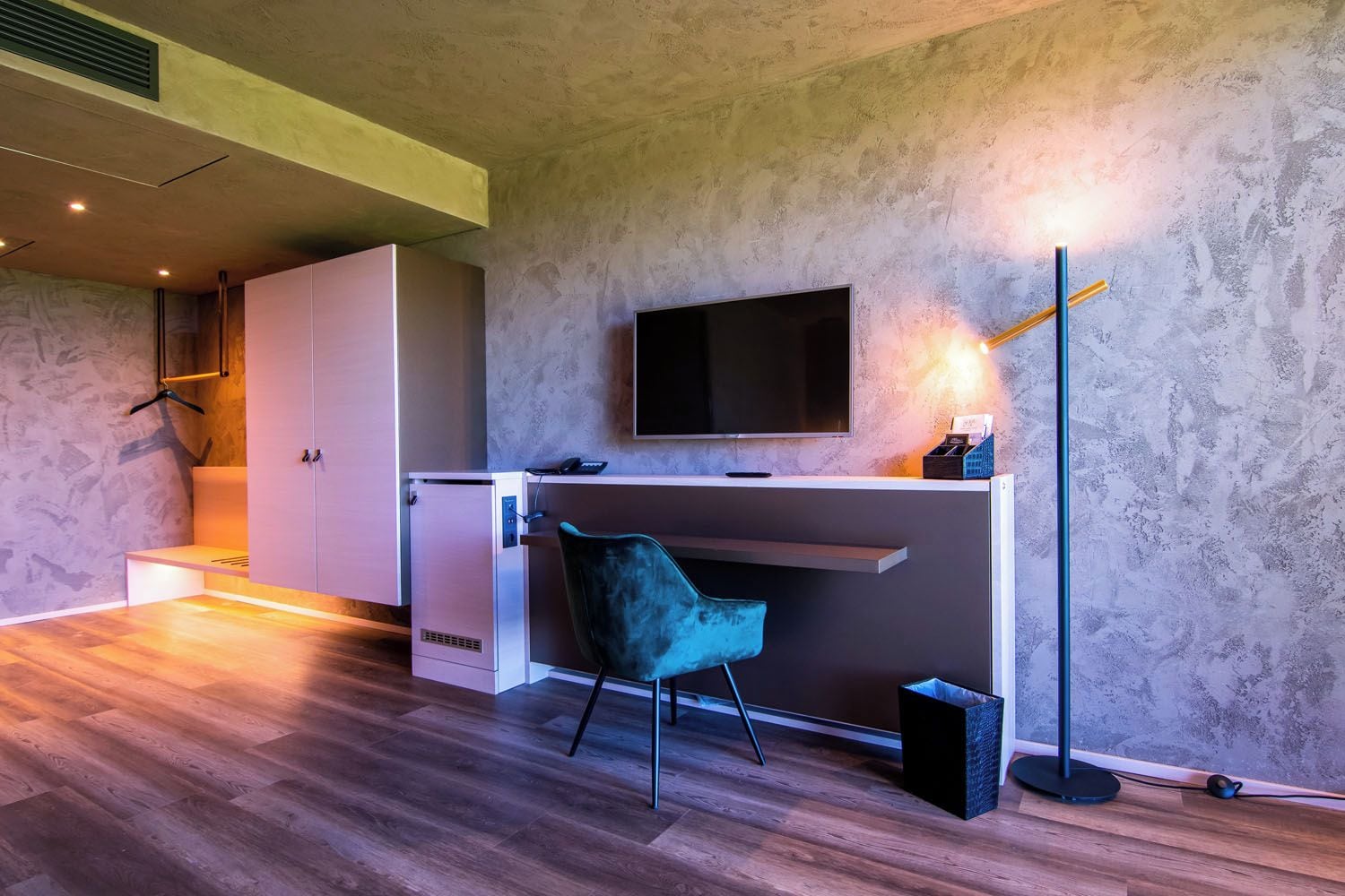 Un espace de bureau moderne comprenant un bureau, une chaise, un téléviseur et un lampadaire.