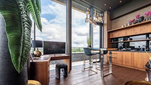 Una cocina moderna con encimera de madera, una zona de comedor con mesa de cristal y un amplio ventanal con vistas al cielo.