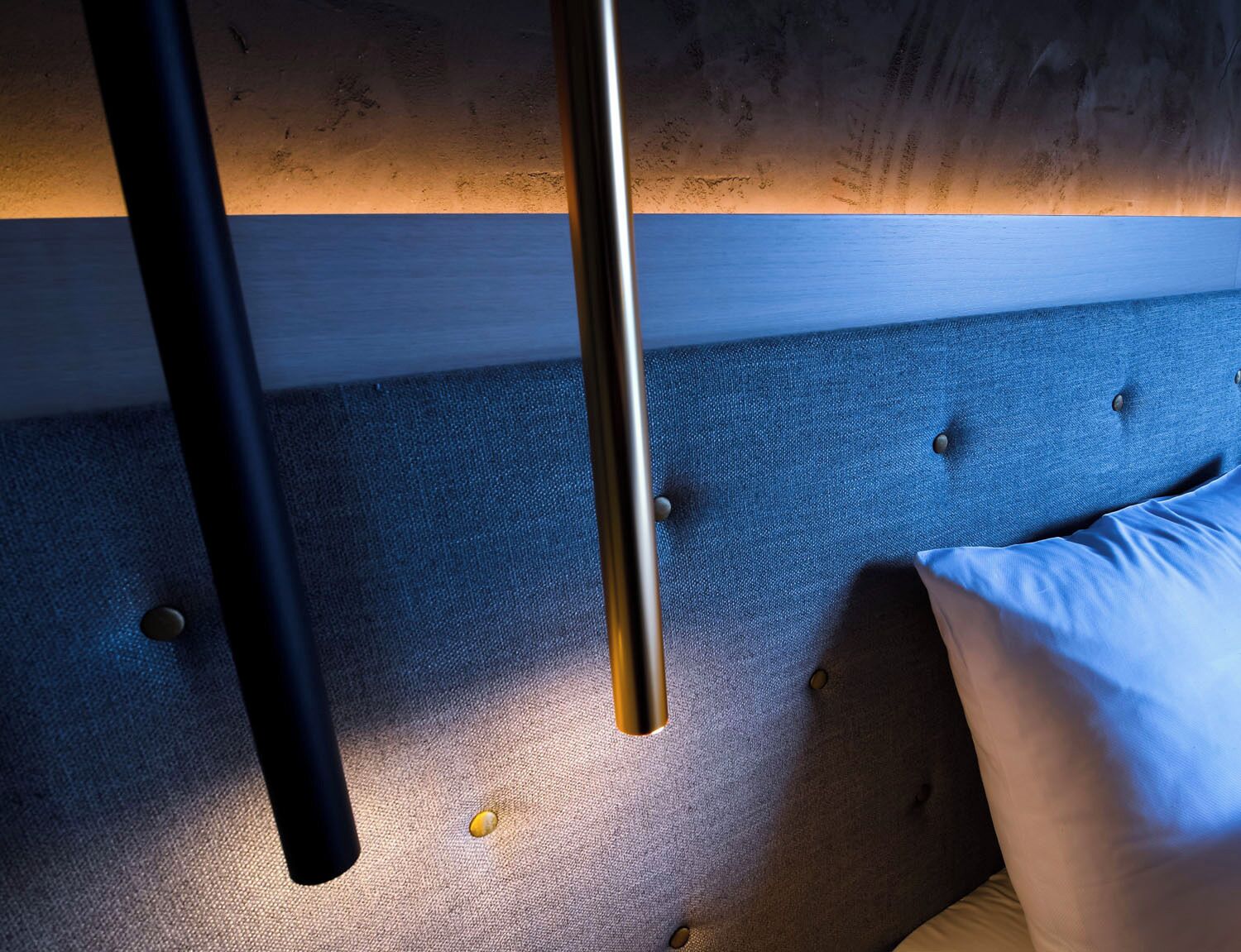 Ein Bett mit blauer Kopfteil, Holzboden und einer Metallstange.