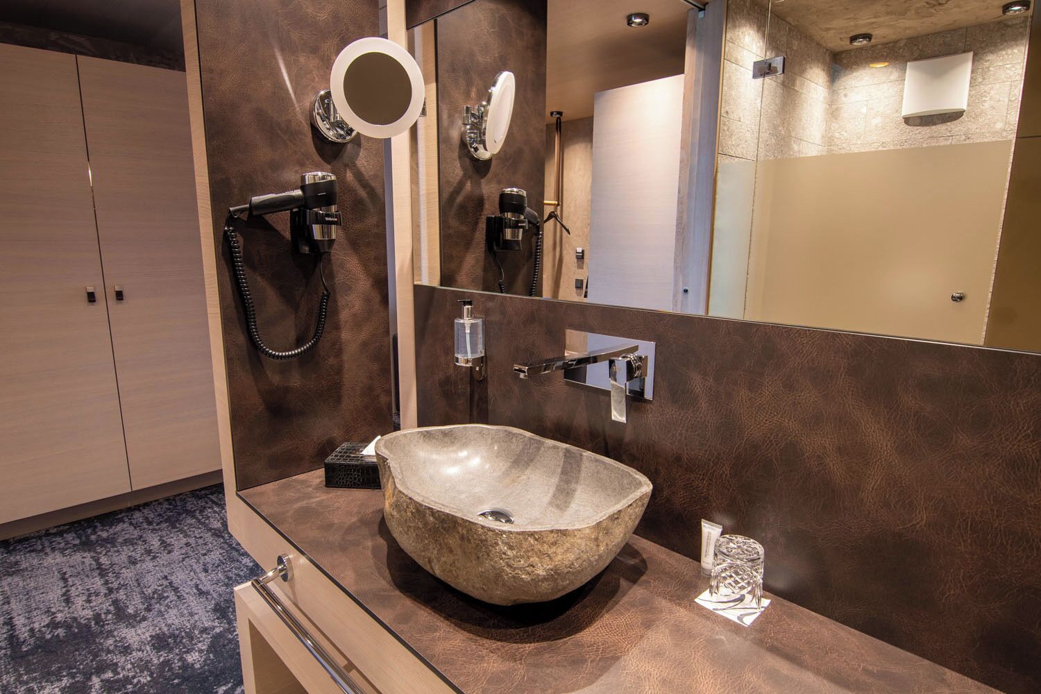 Un bagno moderno con un lavabo in pietra, uno specchio grande e un porta asciugamani.