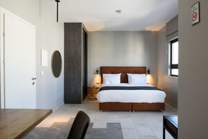 Un dormitorio moderno con una cama grande, mesitas de noche, un escritorio y una silla.