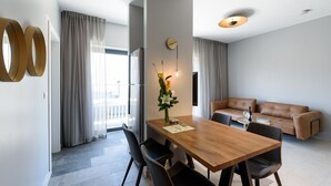 Un salon moderne avec une table à manger en bois, deux chaises, un canapé et une table basse.