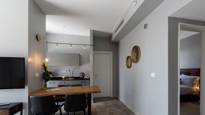 Une cuisine moderne avec un coin repas, un téléviseur et une chambre à coucher visible à travers une porte ouverte.