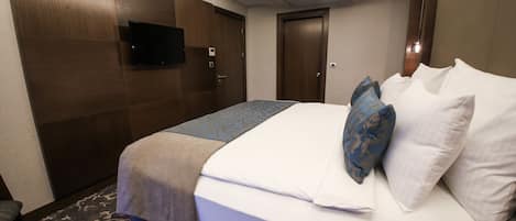 Habitación de hotel con cama, televisor de pantalla plana en la pared y una puerta.