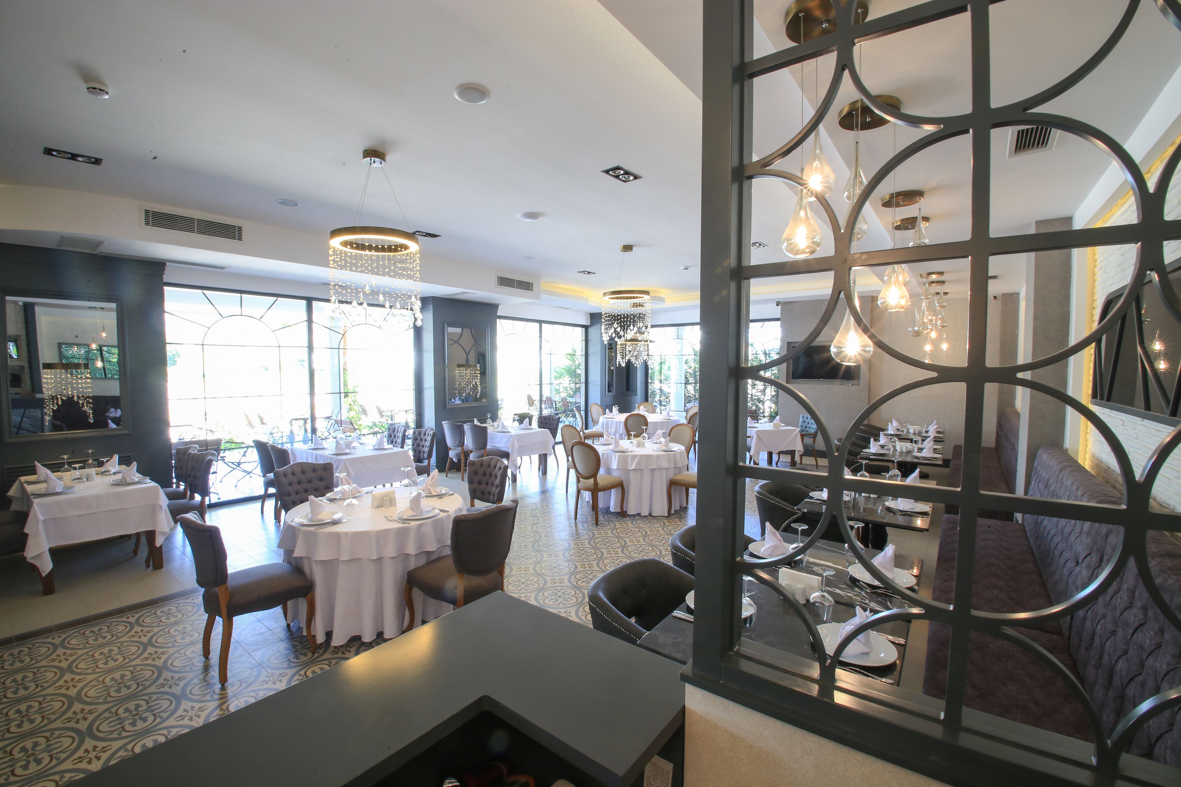 Un restaurant avec des tables rondes, des chaises et des luminaires suspendus.