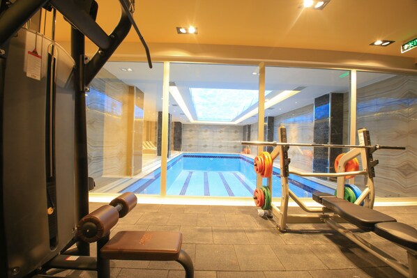 A gym with a view of a swimming pool through glass doors.