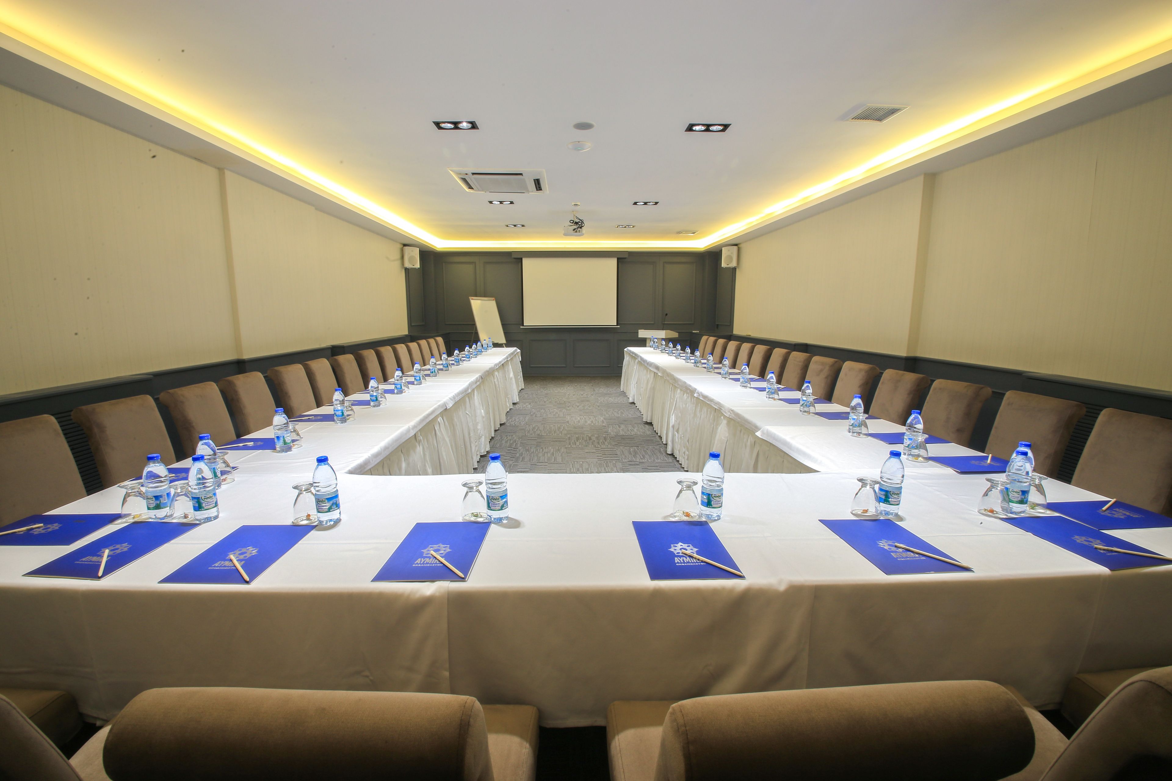 A conference room with a long table, chairs, water bottles, and nameplates.