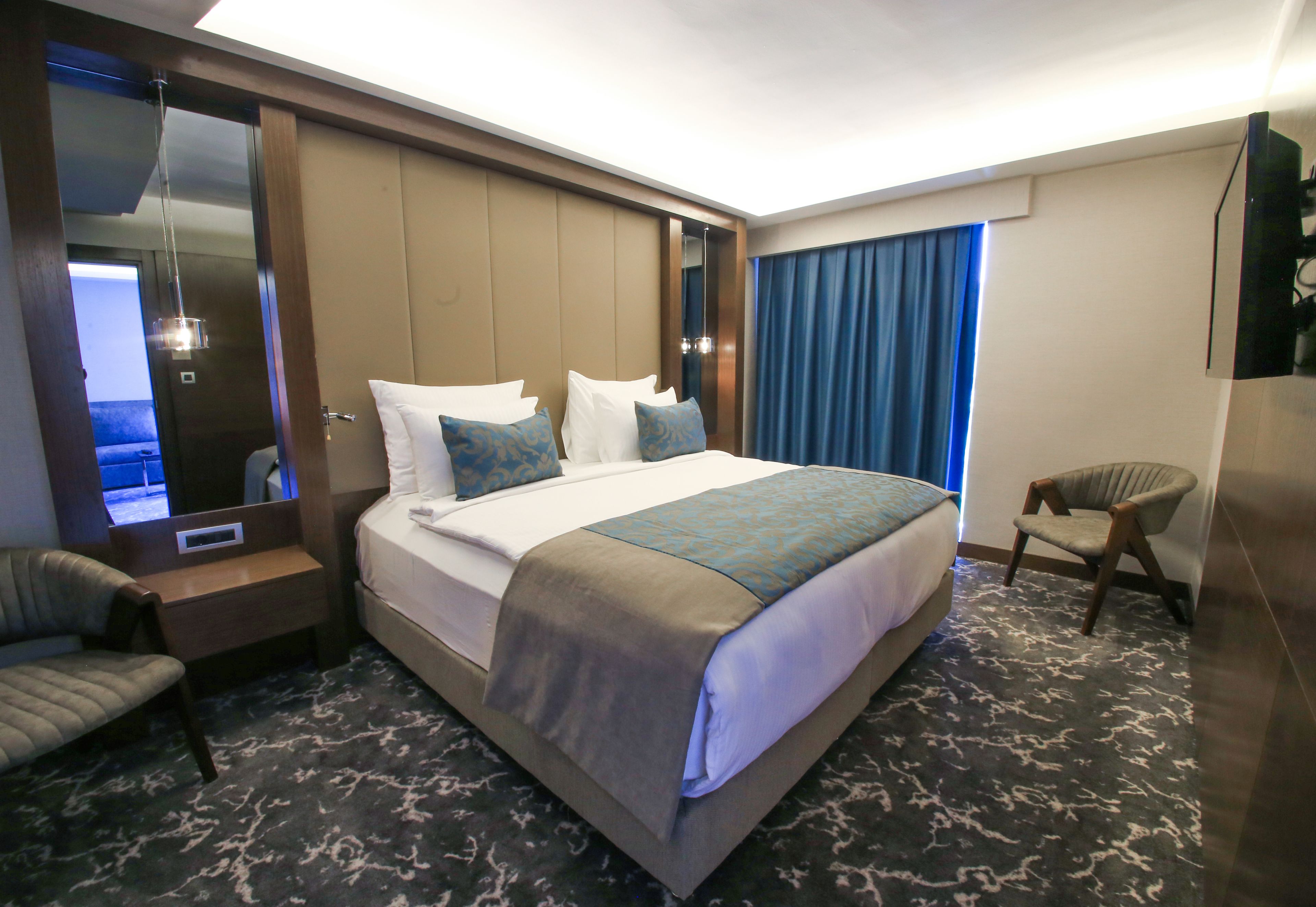 A hotel room with a large bed, a desk, a chair, and a television.