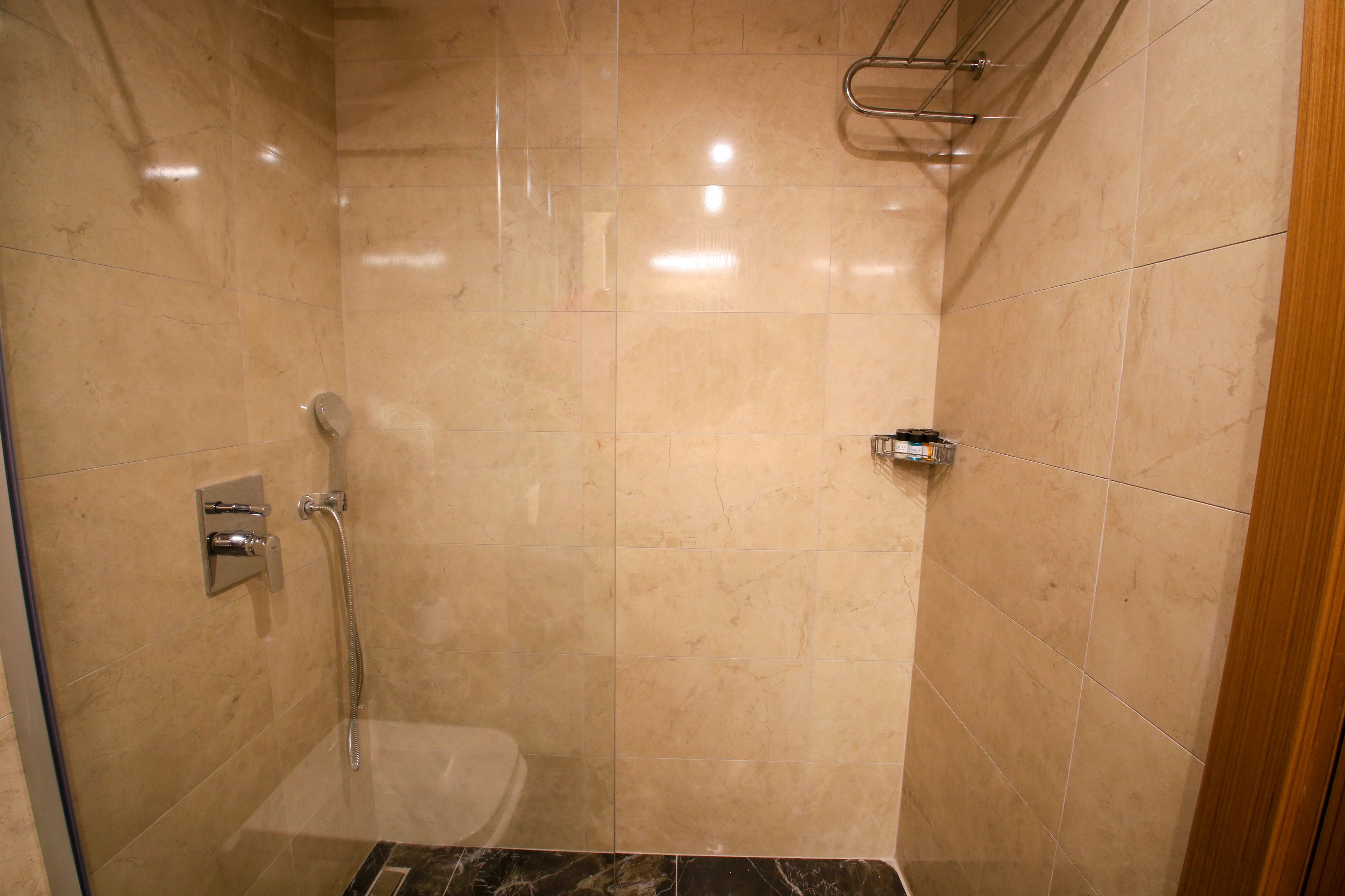 Un pequeño baño con azulejos, puerta de cristal y ducha.