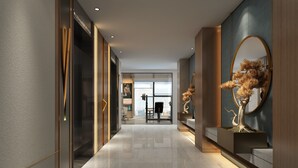 Un hall d’hôtel moderne avec un long couloir, un comptoir d’accueil et un grand miroir orné d’un motif d’arbre décoratif.