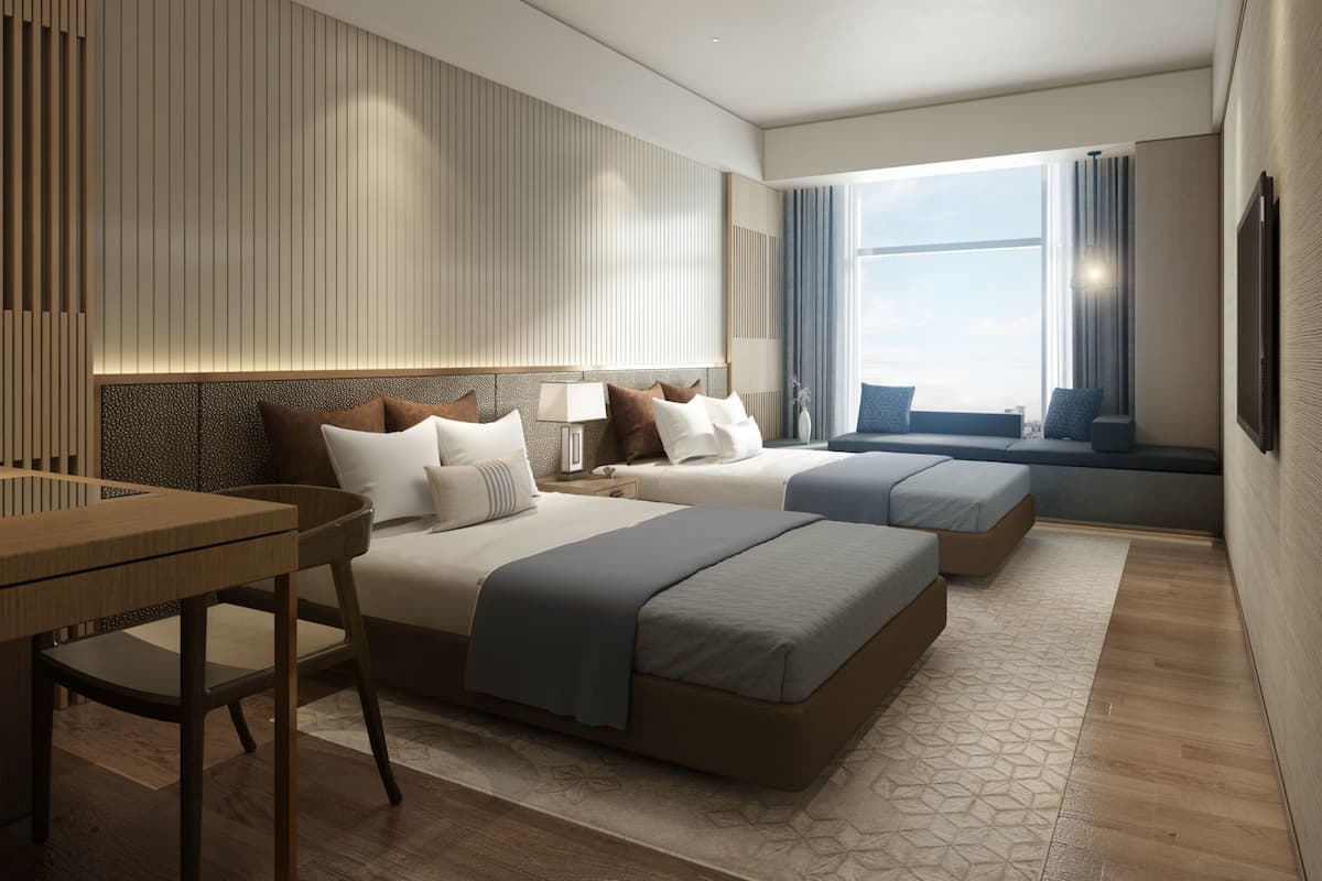 Een moderne hotelkamer met twee bedden, een bureau en een groot raam met uitzicht op de stad.