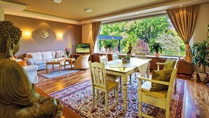A living room with a sofa, TV, and dining area with chairs and a table. - Balance-Hotel am Blauenwald (Badenweiler)