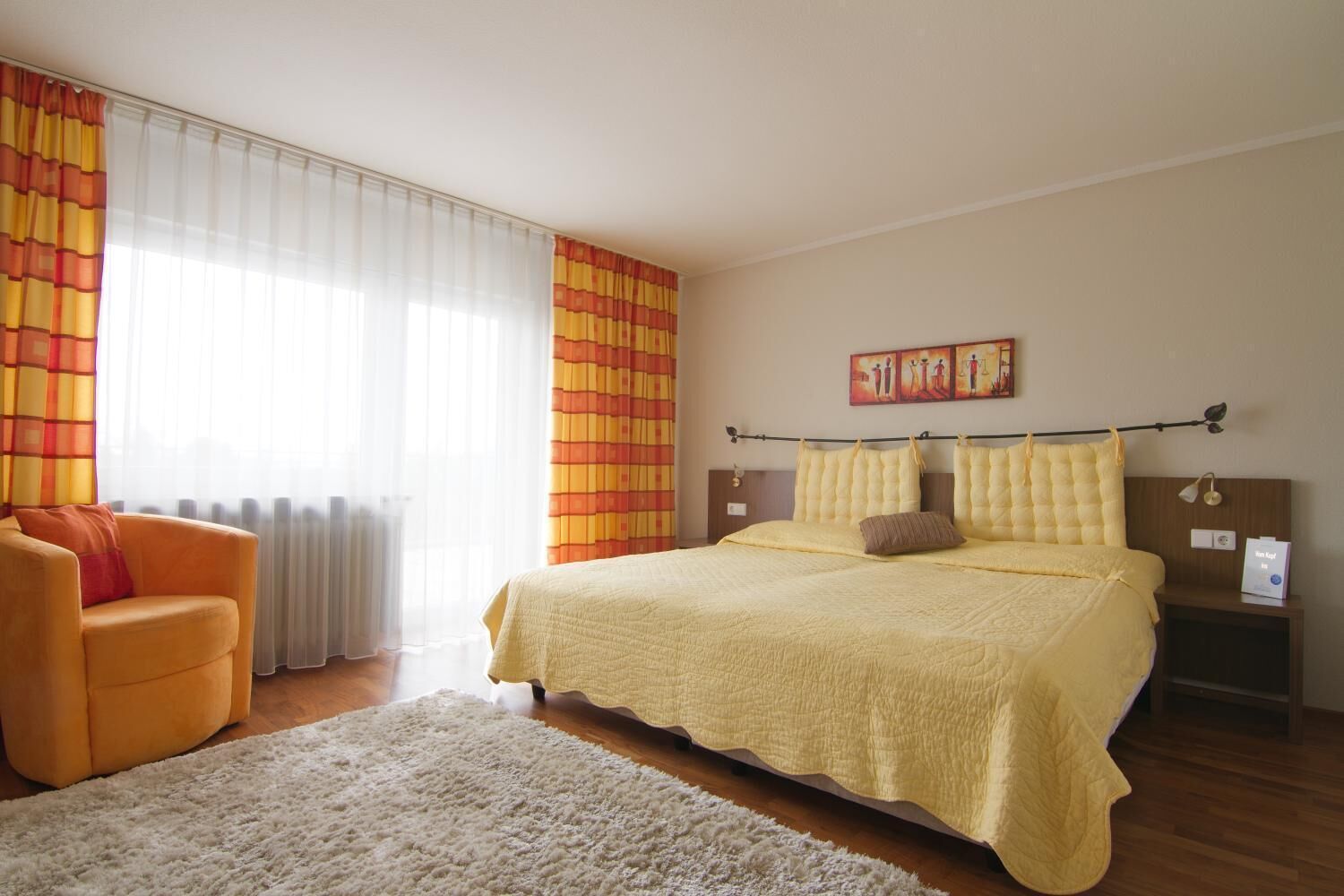 Une chambre à coucher avec un lit, une chaise, une table de chevet et un tableau accroché au mur.