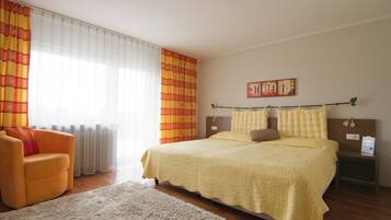 Ein Schlafzimmer mit einem Bett, einem Sessel, einem Nachttisch und einem Bild an der Wand.