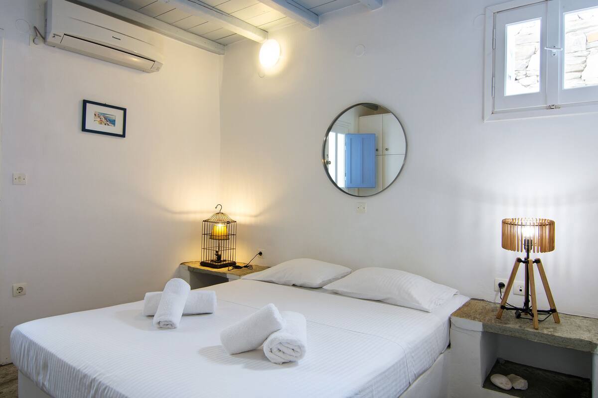 Une chambre d’hôtel avec un lit, une table de chevet avec une lampe, un miroir et un tableau au mur.