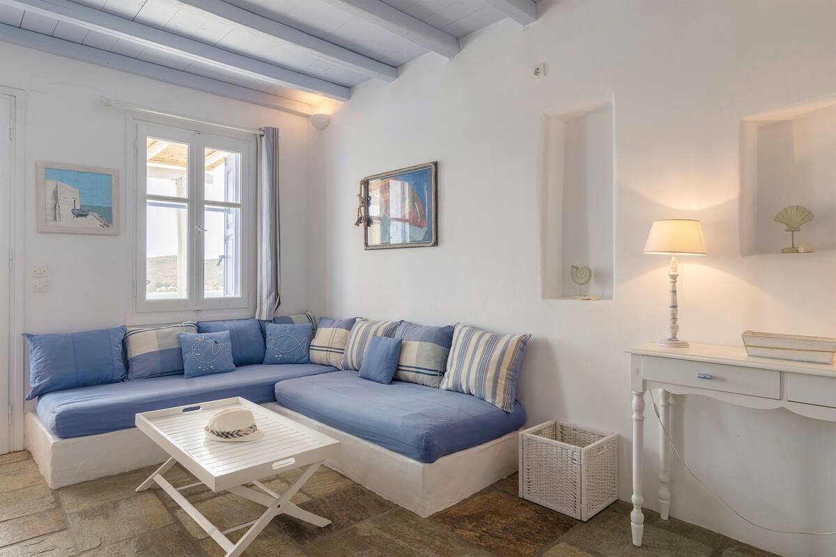 Une pièce avec un canapé bleu, une table blanche et une lampe.