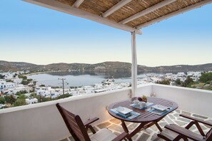 Ein Balkon mit Tisch und Stühlen mit Blick auf eine Küstenstadt mit weißen Gebäuden und einem Wasserlauf.