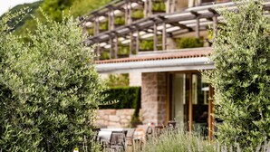 A patio area with outdoor seating and a stone wall. - Hotel Hasslhof (Caldaro Sulla Strada del Vino)