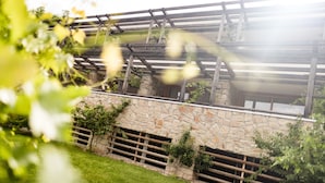 A stone wall with a wooden pergola structure. - Hotel Hasslhof (Caldaro Sulla Strada del Vino)