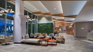 A spacious lobby with modern furniture, a green wall, and a view of the outside. - The Westin Irving Convention Center at Las Colinas (Irving)