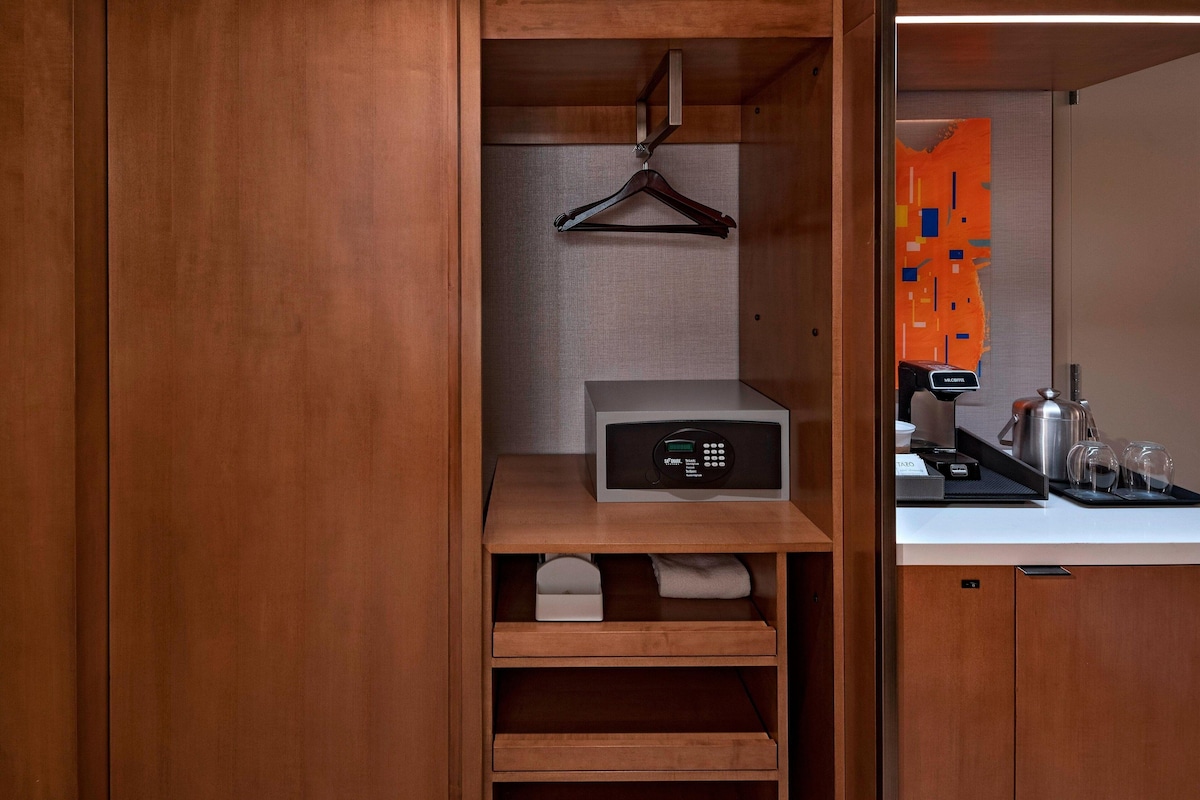 Un baño moderno y funcional con tocador de madera, toallero y cafetera sobre la encimera.